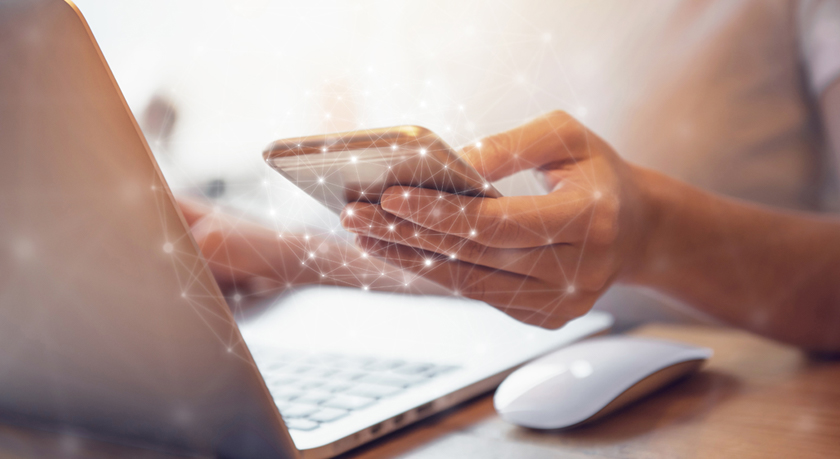 Woman hand holding mobile phone and laptop data synchronization